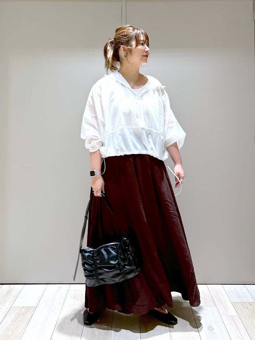 ブラック系のショルダーバッグ、ブラック系のパンプス、ブラウン系のスカートを着用したレディースの秋コーディネートの1枚目の写真