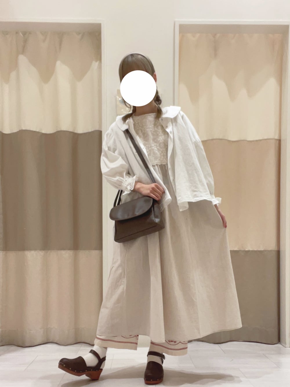 ホワイト系のシャツ/ブラウス、ホワイト系のワンピース、ブラウン系のハンドバッグを着用したレディースの春コーディネートの1枚目の写真