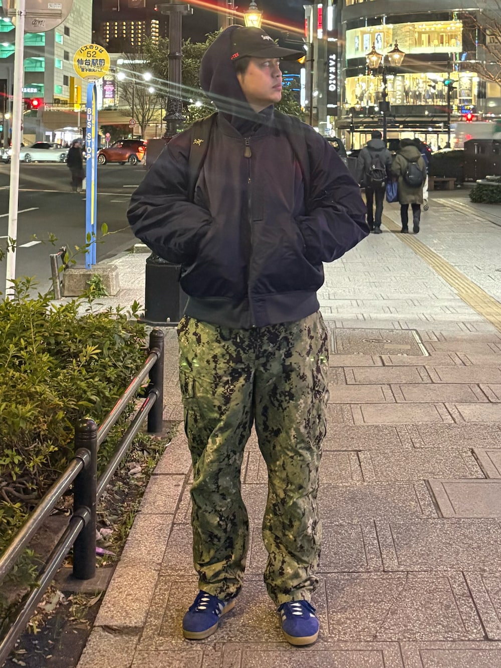 ブルー系のミリタリージャケット、グリーン系のカーゴパンツ、ブルー系のスニーカーを着用したメンズの春コーディネートの1枚目の写真