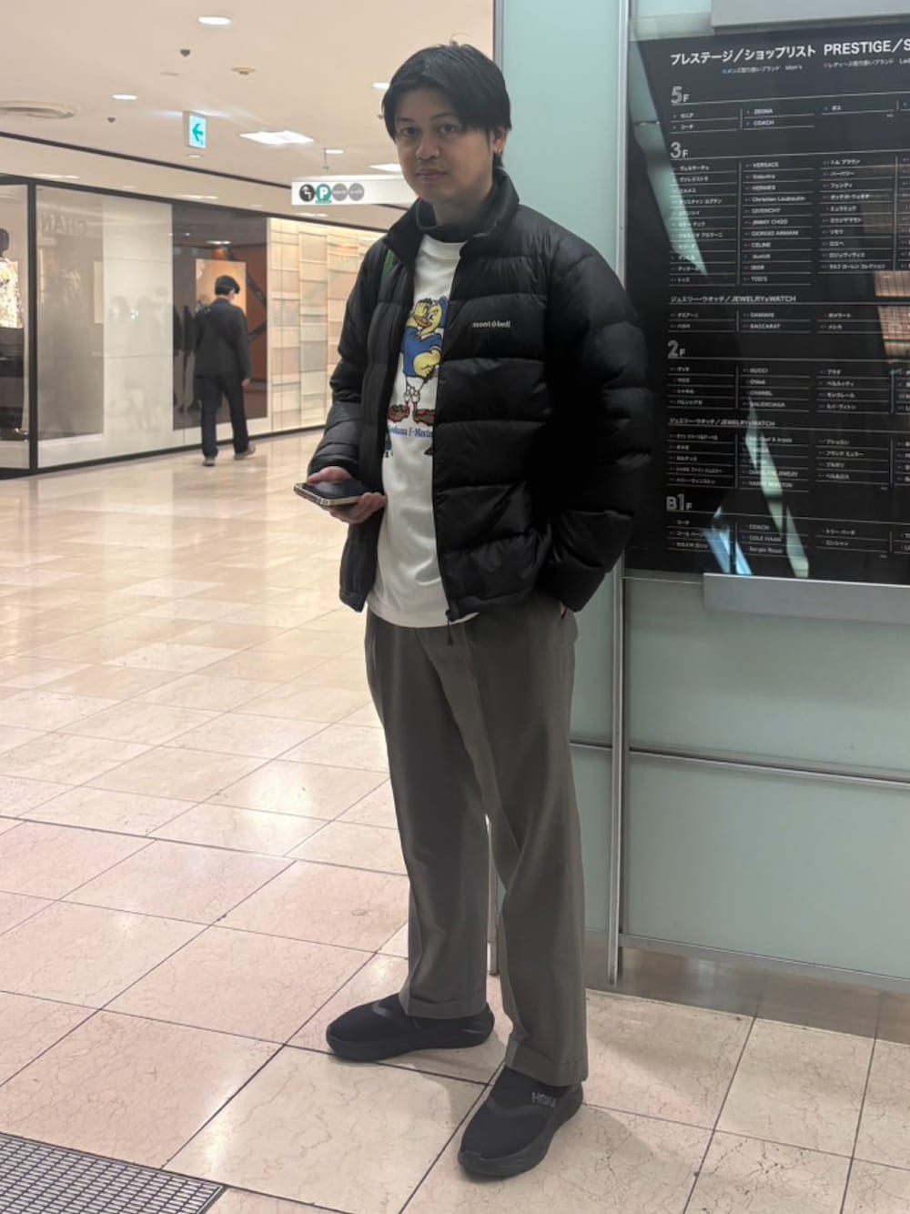 ブラック系のダウンジャケット/コート、グレー系のスラックス、ブラック系のスニーカーを着用したメンズの春コーディネートの1枚目の写真