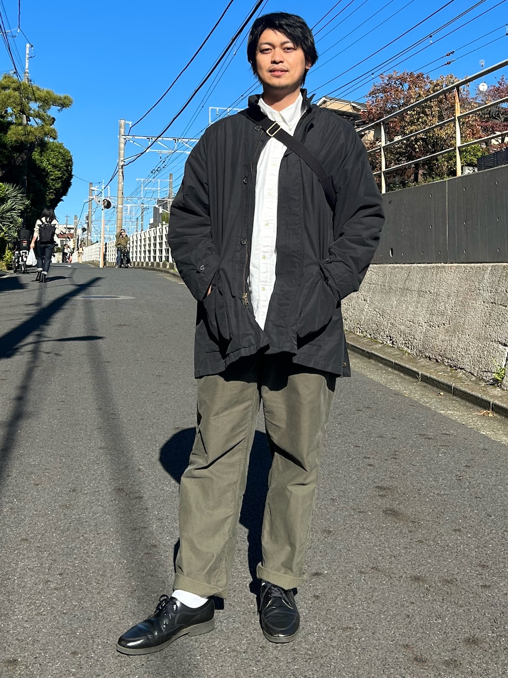 ブラック系のジャケット/アウター、ホワイト系のシャツ/ブラウス、グリーン系のチノパンツを着用したメンズの冬コーディネートの1枚目の写真