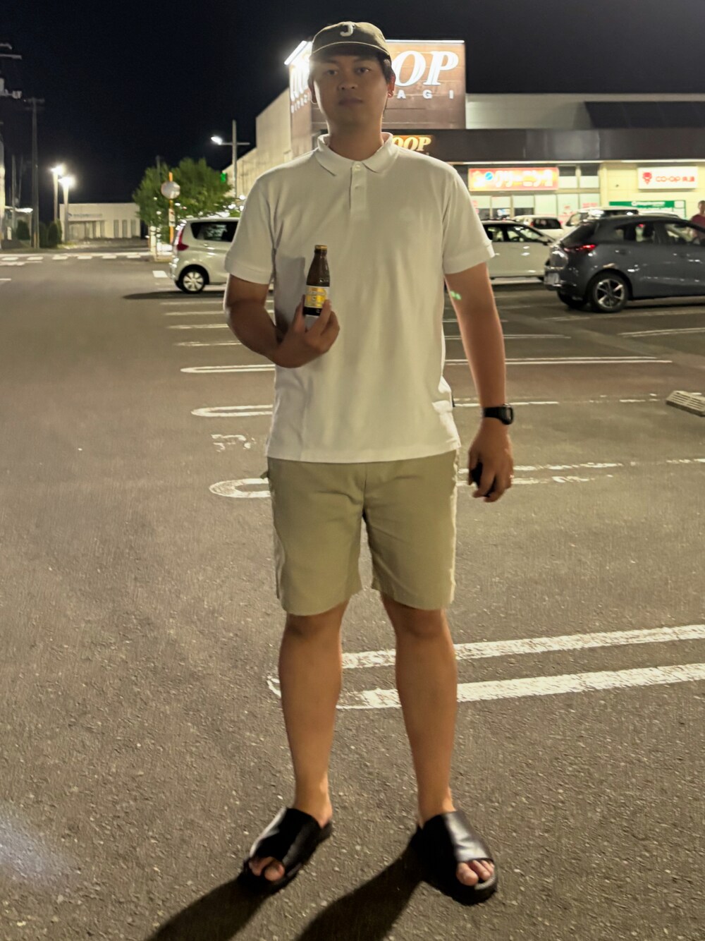 ホワイト系のポロシャツ、ベージュ系のその他パンツ、ブラック系のサンダルを着用したメンズの夏コーディネートの1枚目の写真