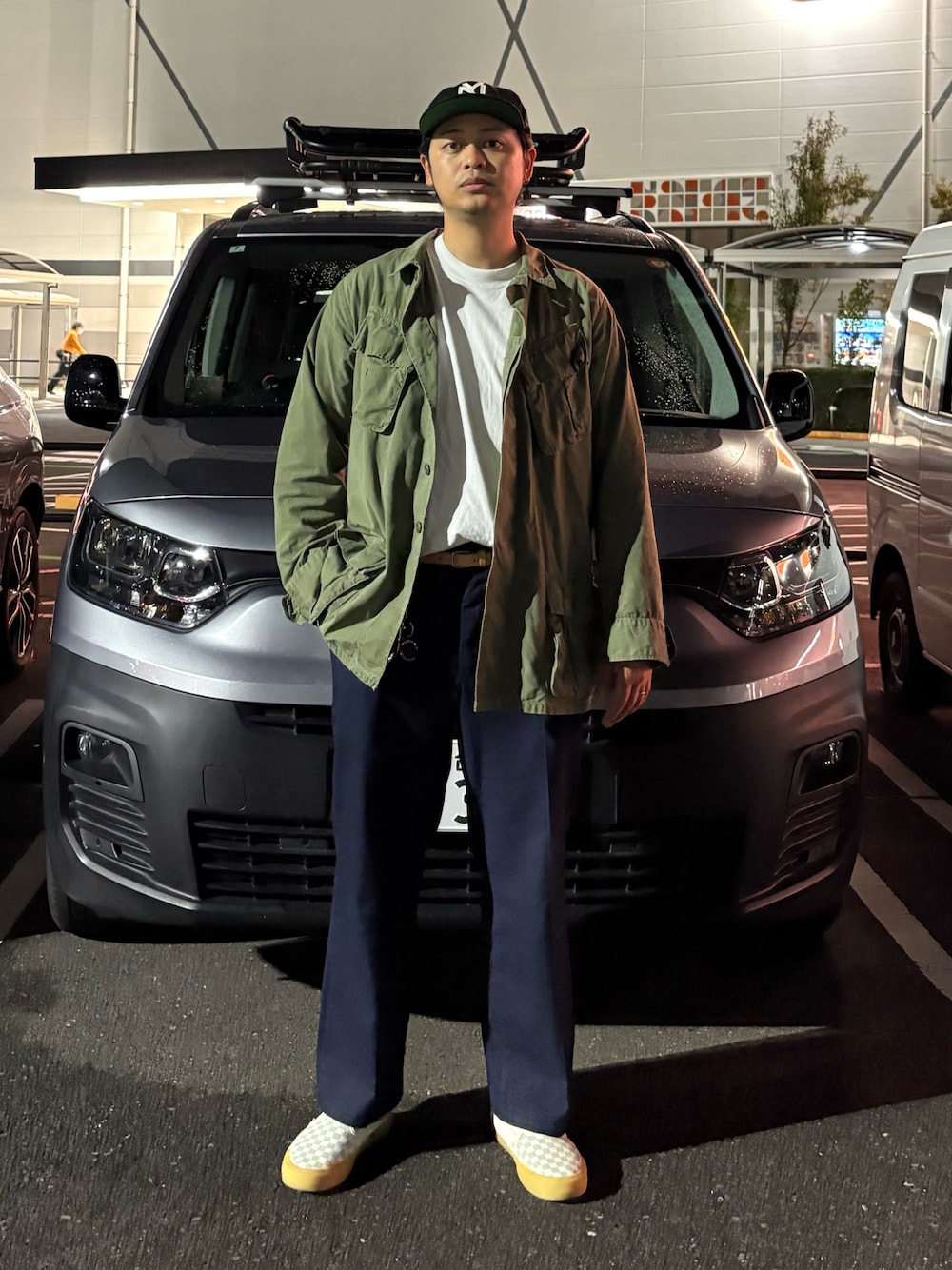 ホワイト系のTシャツ/カットソー、グリーン系のミリタリージャケット、ブルー系のパンツを着用したメンズの秋コーディネートの1枚目の写真