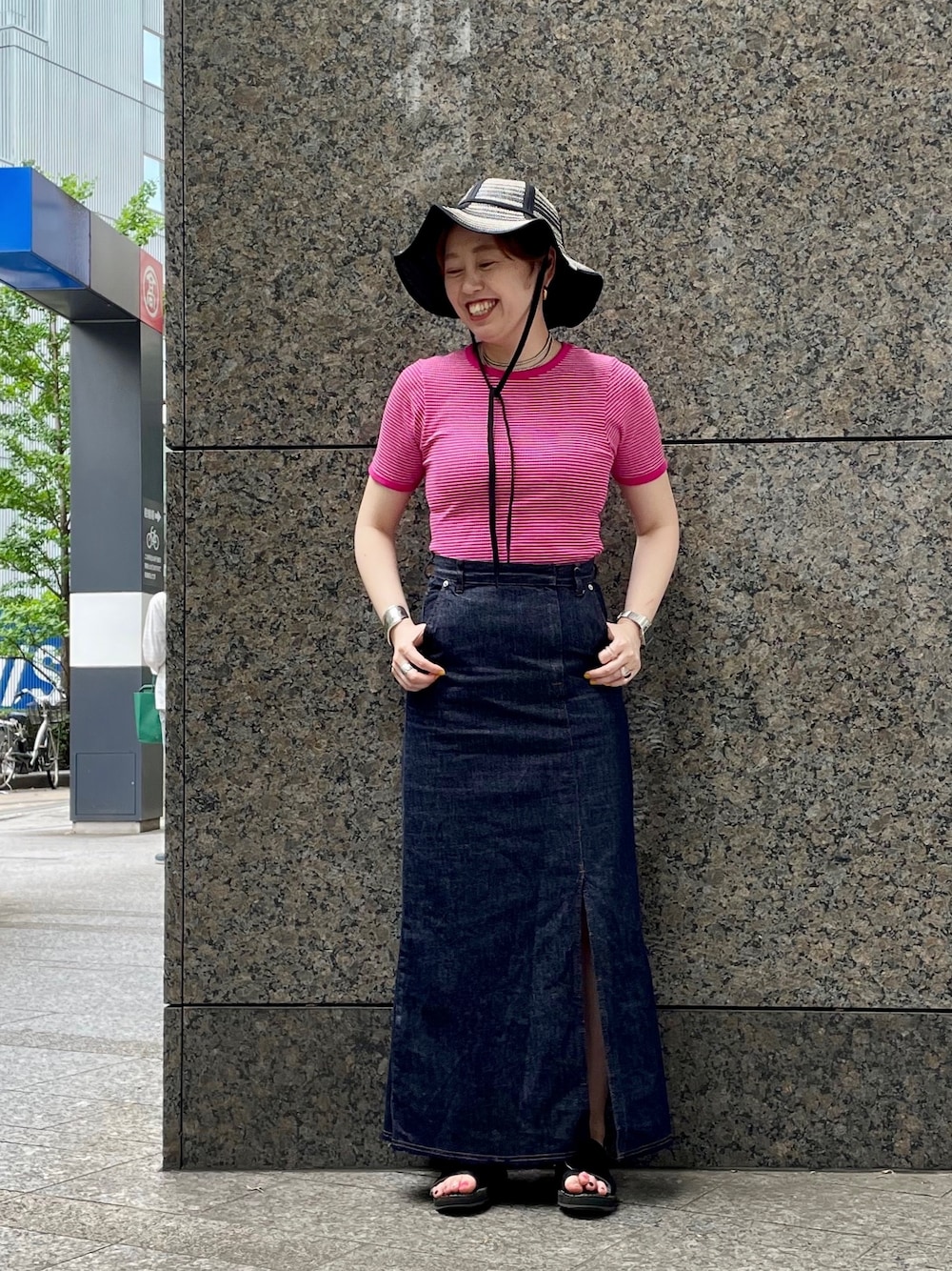 ブルー系のデニムスカート、ブラック系のサンダル、ピンク系のTシャツ/カットソーを着用したレディースの夏コーディネートの1枚目の写真