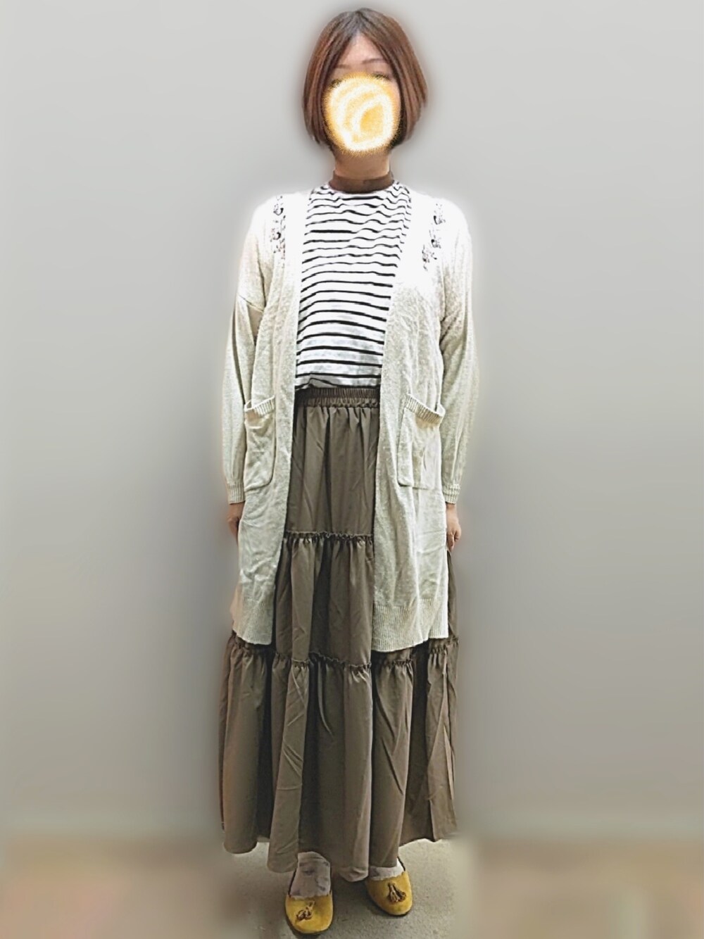 ブラウン系のTシャツ/カットソー、ブラウン系のスカート、ベージュ系のカーディガン/ボレロを着用したレディースの冬コーディネートの2枚目の写真