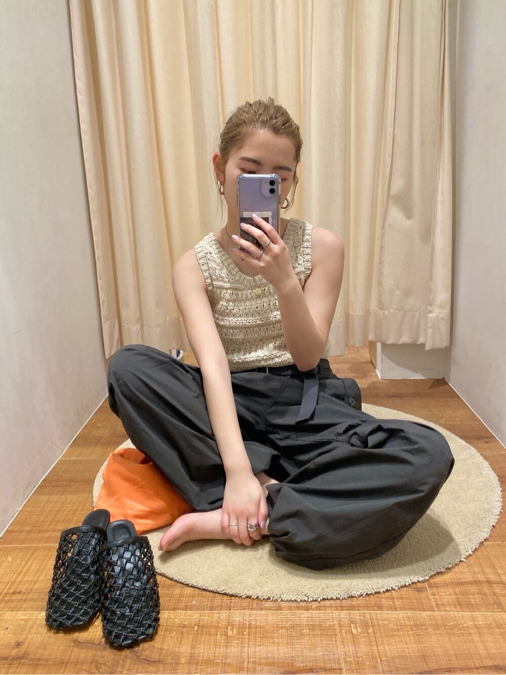 ブラック系のサンダル、ホワイト系のニット/セーター、オレンジ系のシャツ/ブラウスを着用したレディースの春コーディネートの1枚目の写真