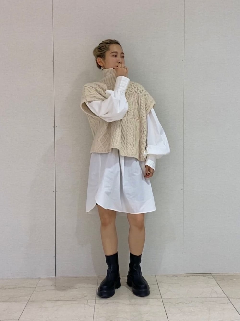 ホワイト系のシャツ/ブラウス、ホワイト系のニット/セーター、ブラック系のブーツを着用したレディースの秋コーディネートの1枚目の写真