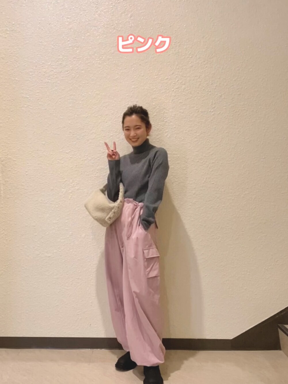 グレー系のニット/セーター、ピンク系のカーゴパンツ、ホワイト系のハンドバッグを着用したレディースの冬コーディネートの1枚目の写真