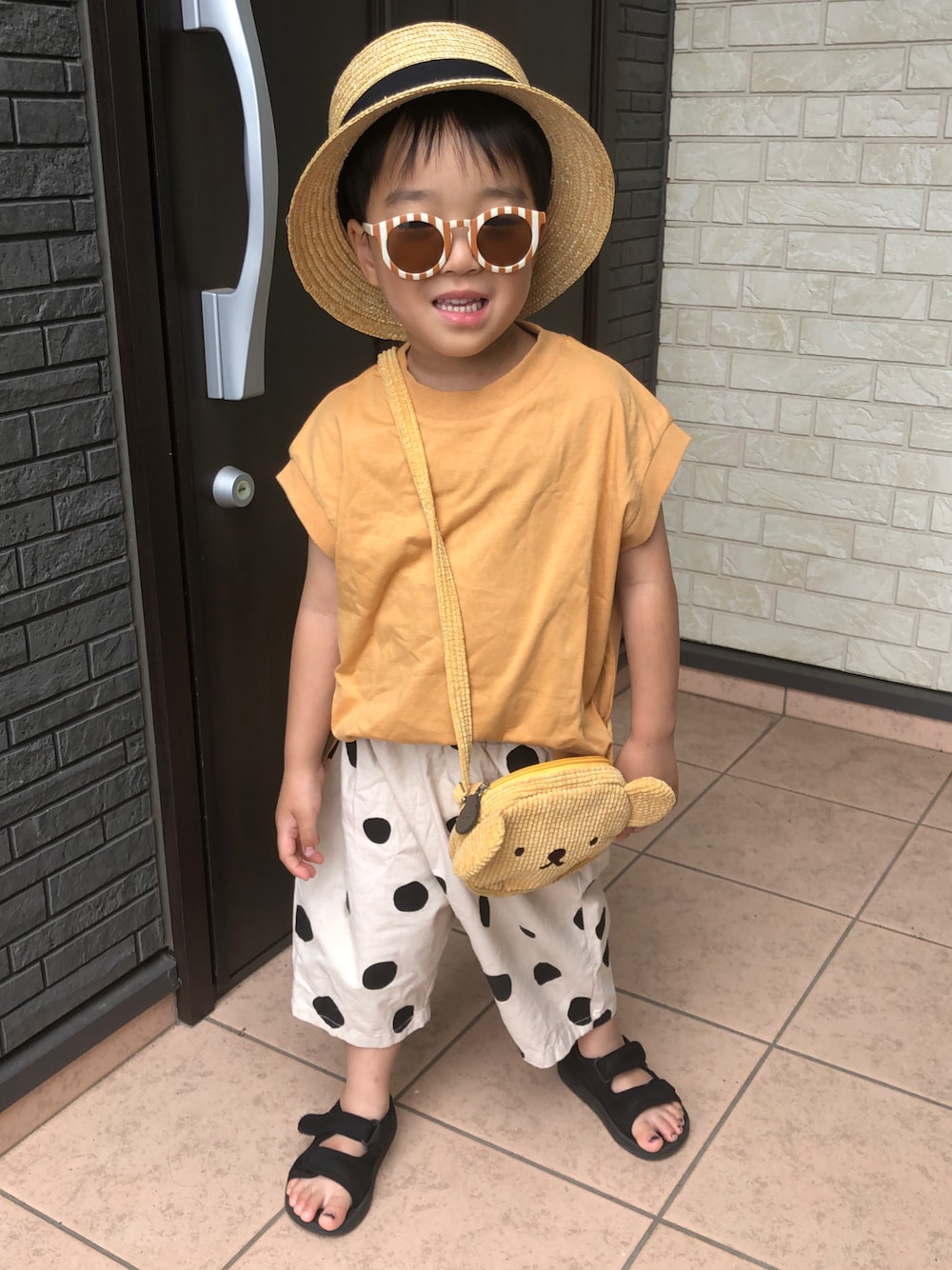 イエロー系のタンクトップ、ベージュ系のその他パンツ、ブラック系のサンダルを着用したキッズの夏コーディネートの1枚目の写真