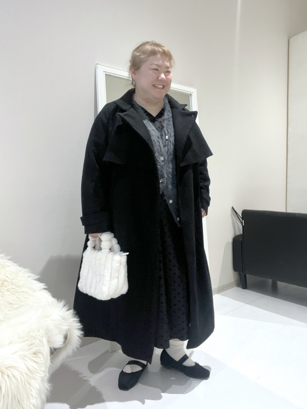 ブラック系のチェスターコート、ブラウン系のニット/セーター、グレー系のワンピースを着用したレディースの冬コーディネートの1枚目の写真
