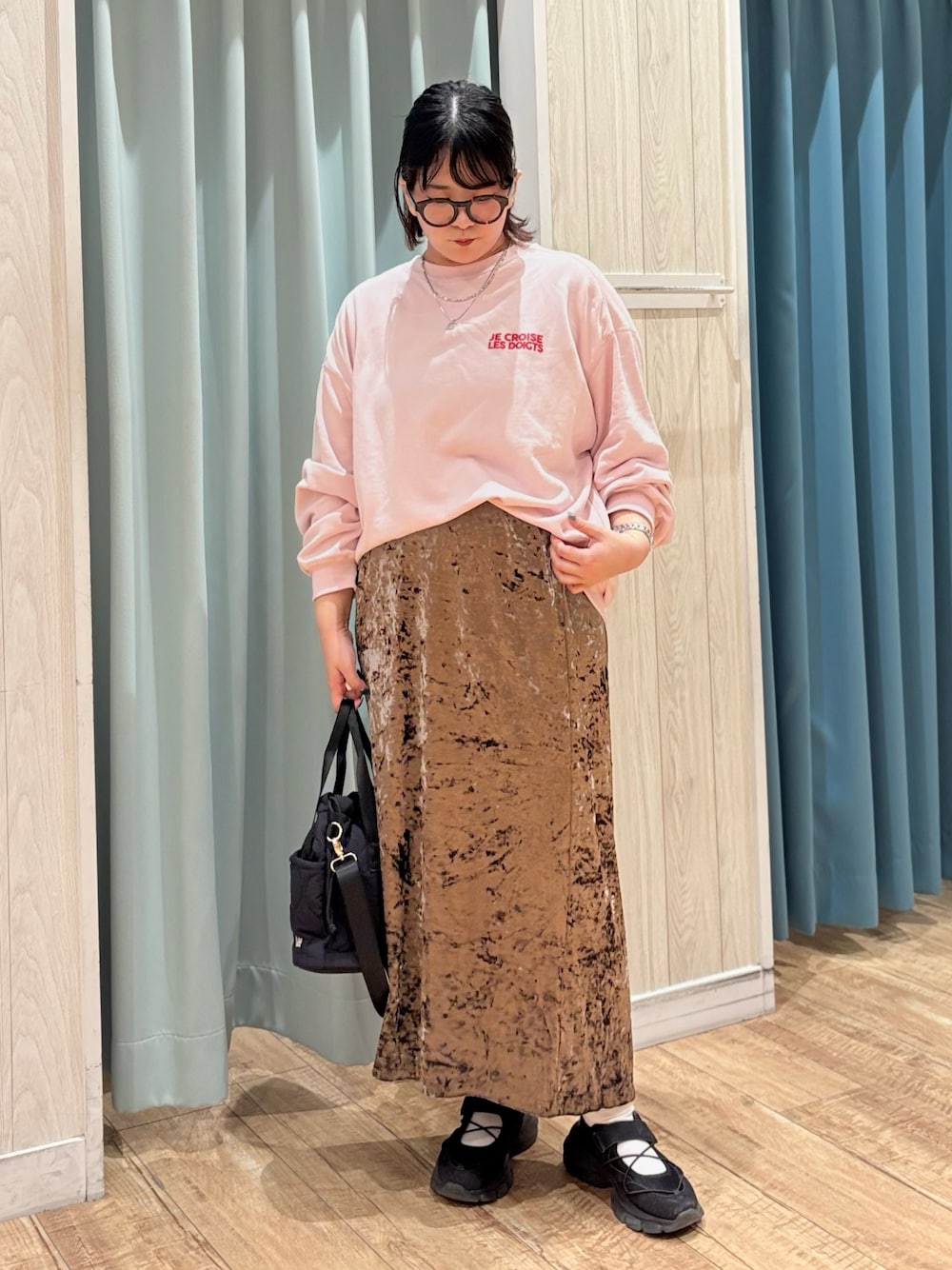 ピンク系のスウェット、ブラウン系のスカート、ブラック系のショルダーバッグを着用したレディースの秋コーディネートの1枚目の写真