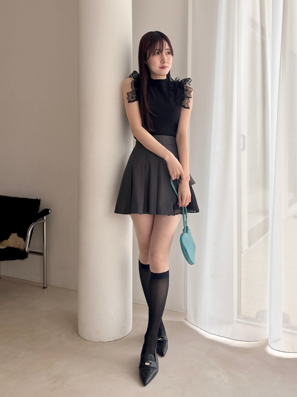 ブラック系のパンプス、グレー系のスカート、ブラック系のニット/セーターを着用したレディースの春コーディネートの1枚目の写真