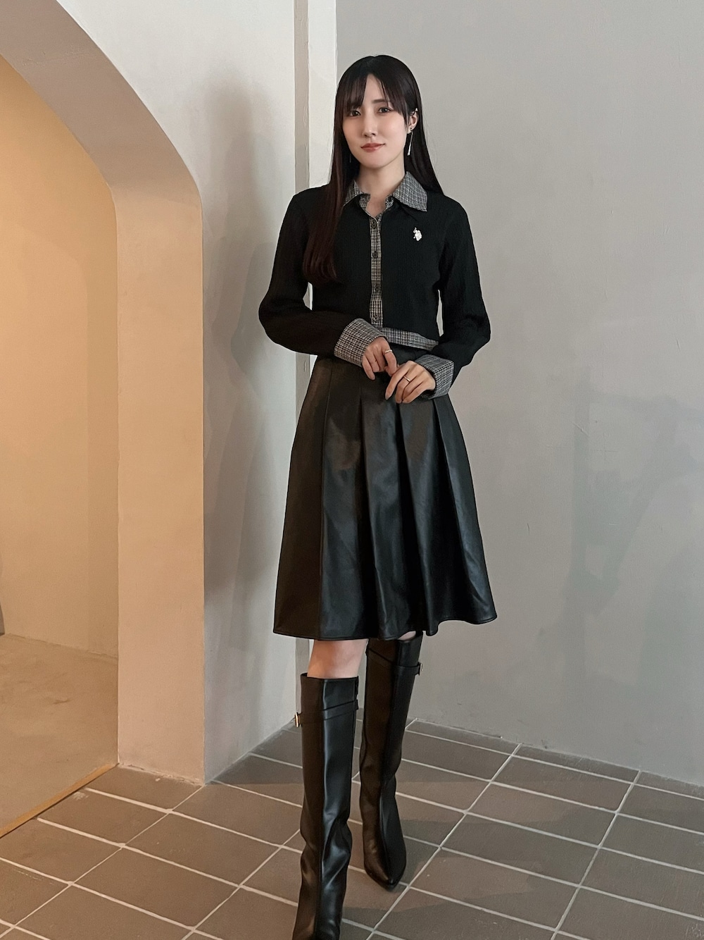 ブラック系のスカート、ブラック系のカーディガン/ボレロ、ブラック系のブーツを着用したレディースの秋コーディネートの1枚目の写真