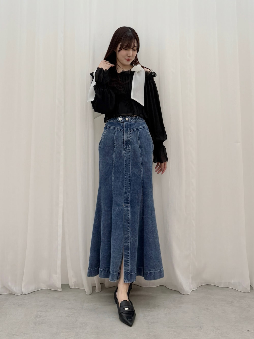 ブラック系のシャツ/ブラウス、ブルー系のスカート、ブラック系のパンプスを着用したレディースの春コーディネートの1枚目の写真