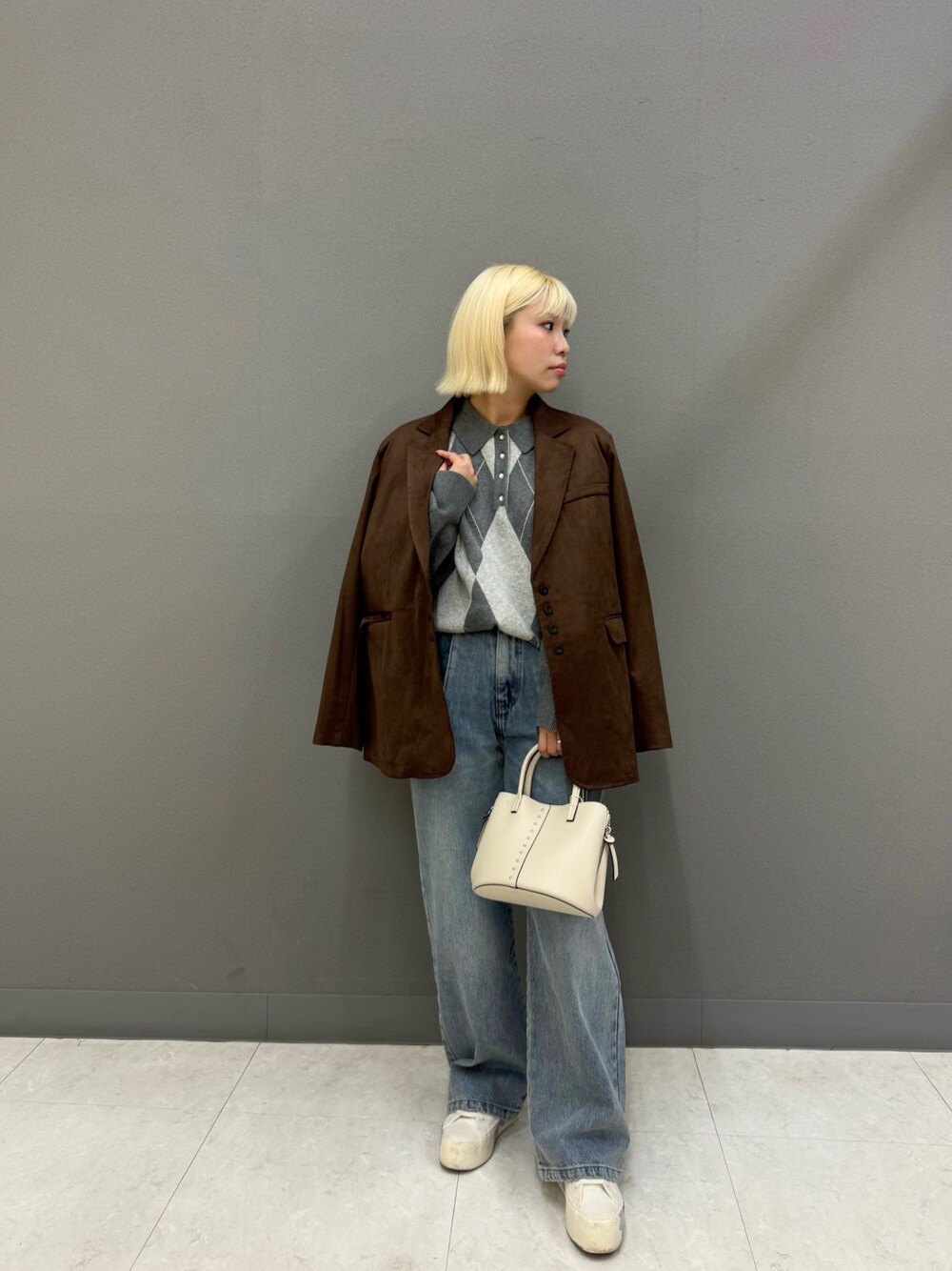 グレー系のニット/セーター、ブルー系のデニムパンツ、ブラウン系のその他アウターを着用したレディースの秋コーディネートの1枚目の写真