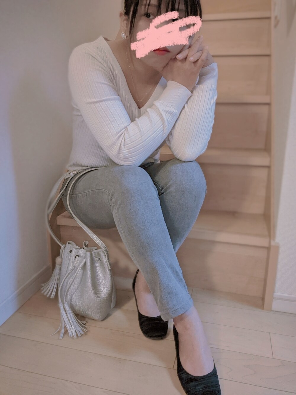 グレー系のデニムパンツ、ブラック系のパンプス、ホワイト系のニット/セーターを着用したレディースの春コーディネートの1枚目の写真