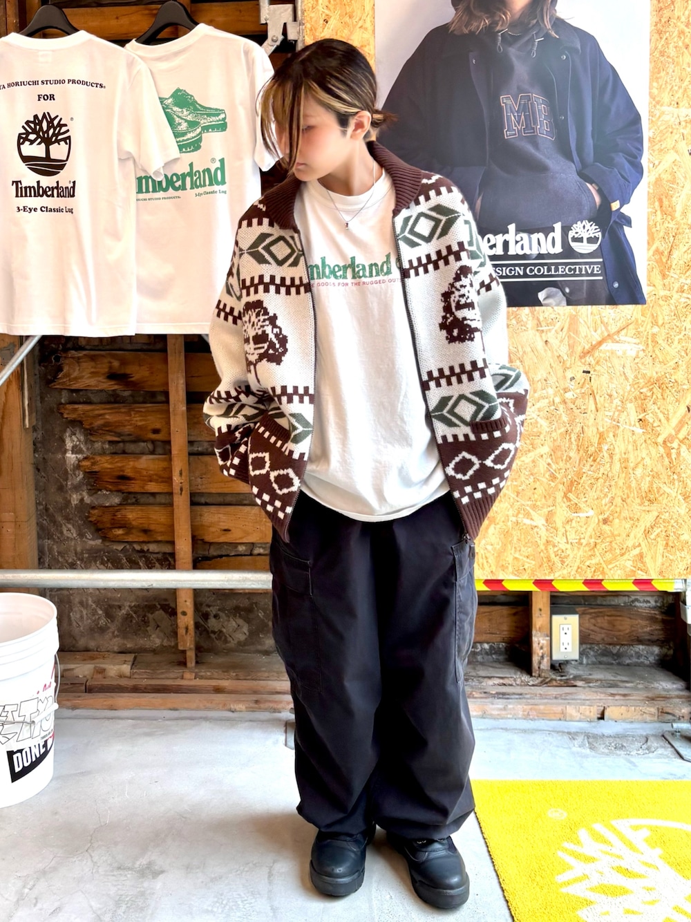 ブラウン系のニット/セーター、ブラック系のブーツ、ホワイト系のTシャツ/カットソーを着用したレディースの秋コーディネートの1枚目の写真