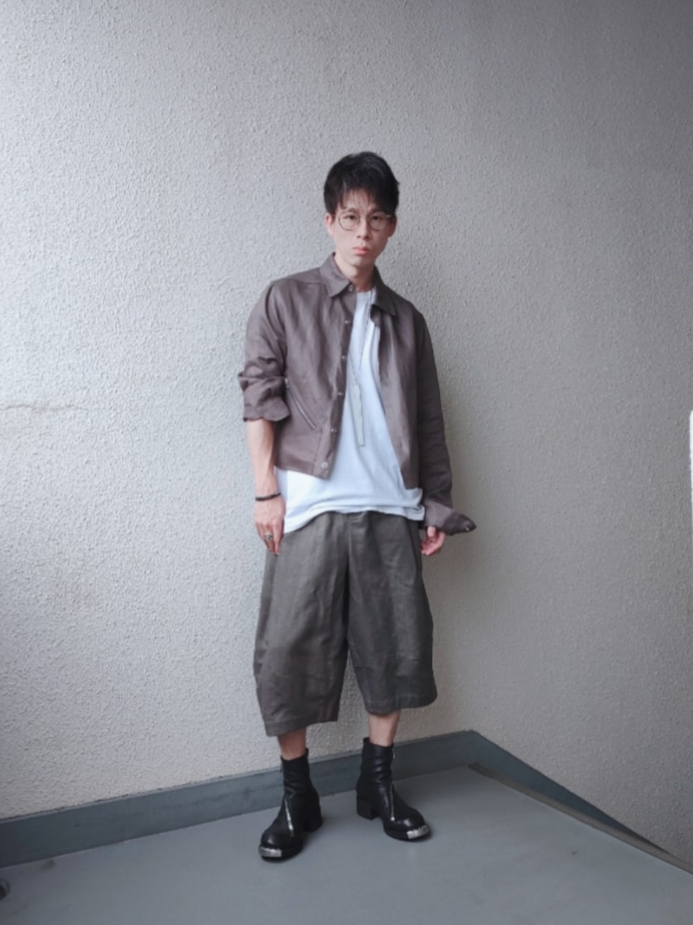 グレー系のブルゾン、グレー系のデニムパンツ、ブラック系のブーツを着用したメンズの夏コーディネートの1枚目の写真