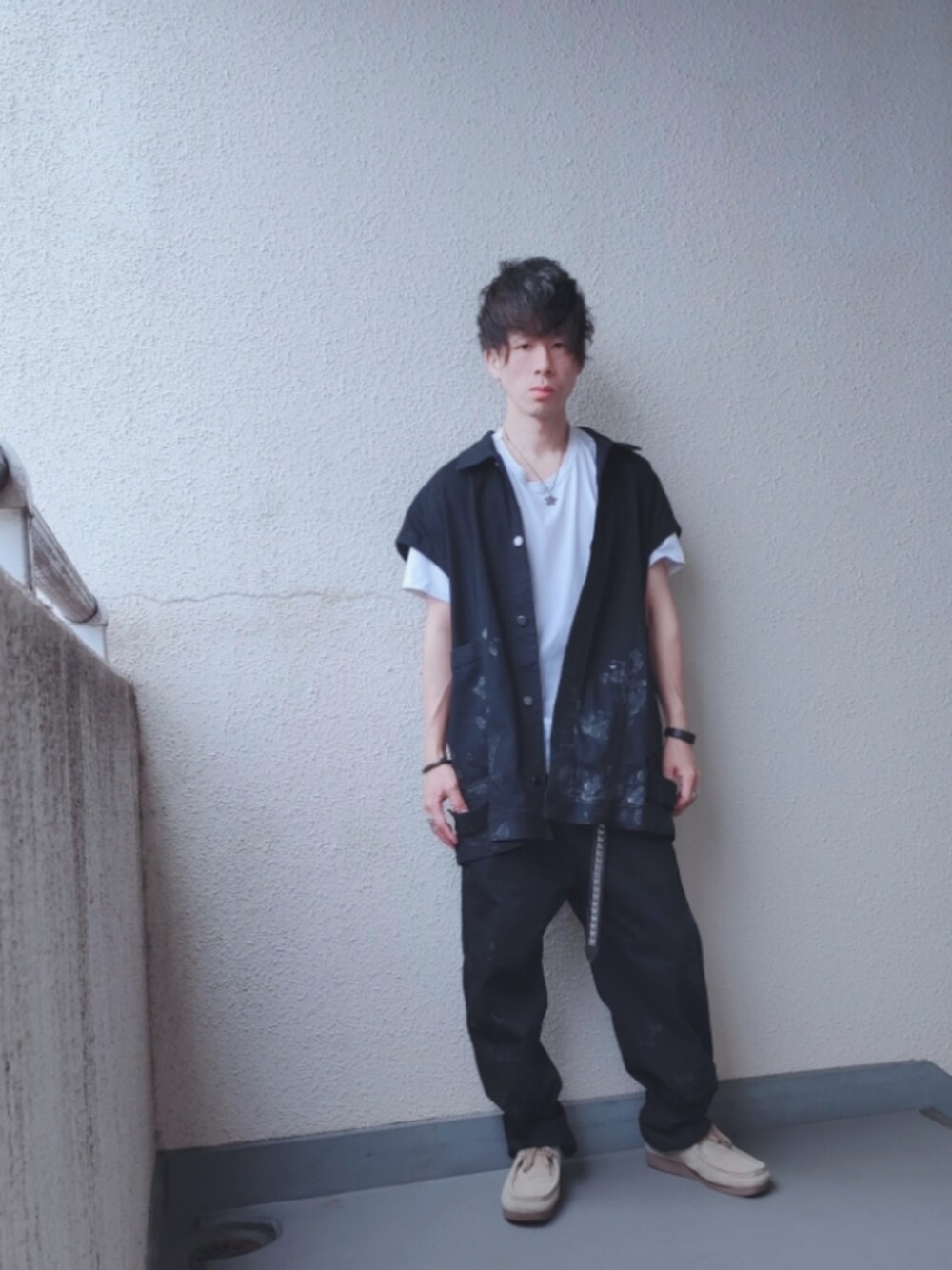 ブラック系のデニムパンツ、ブラック系のベスト、ベージュ系のシューズを着用したメンズの春コーディネートの1枚目の写真