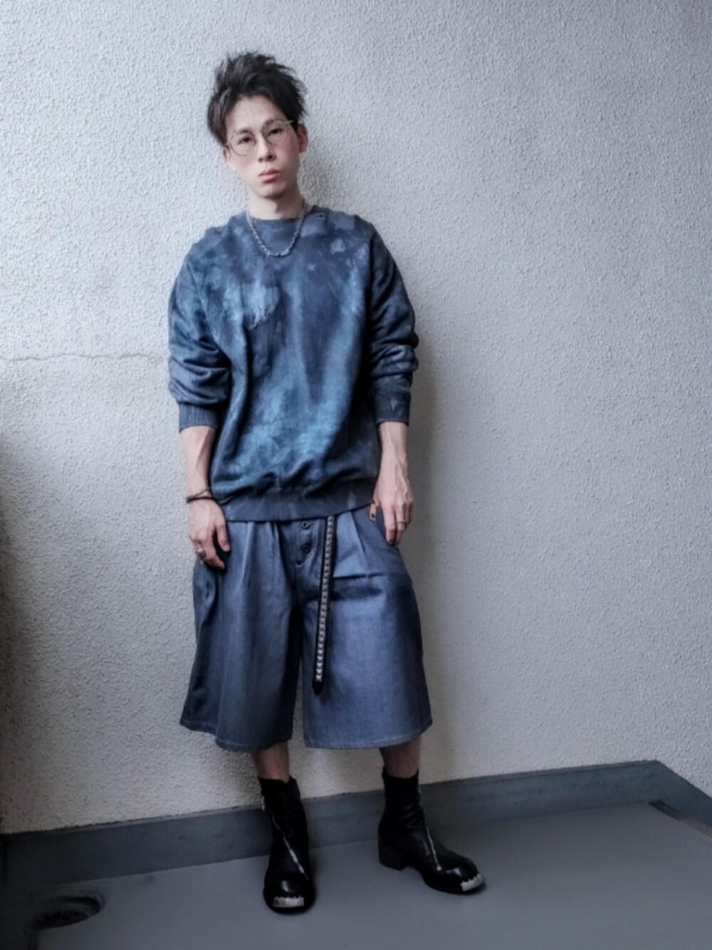 グリーン系のスウェット、ブラック系のブーツ、ブルー系のデニムパンツを着用したメンズの春コーディネートの1枚目の写真