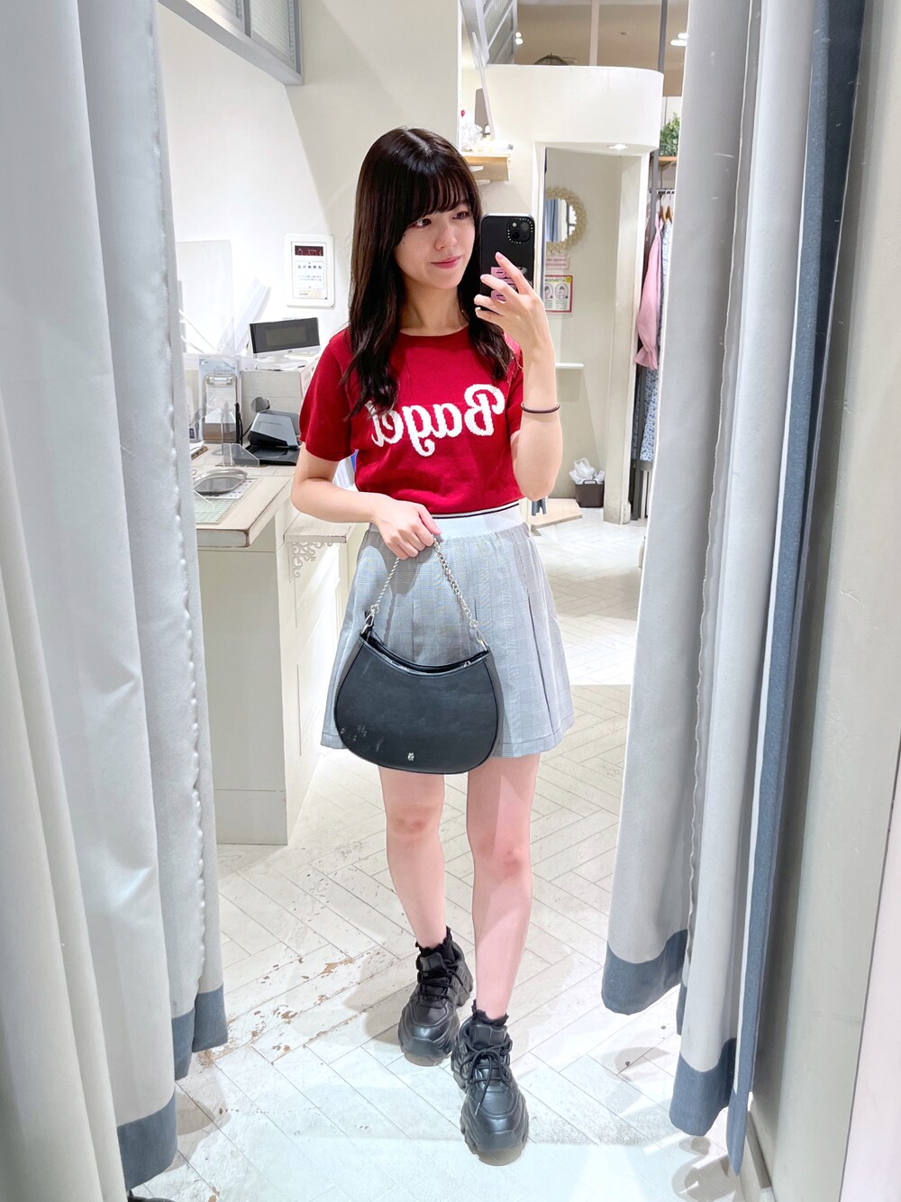 レッド系のニット/セーター、グレー系のスカート、ブラック系のショルダーバッグを着用したレディースの夏コーディネートの1枚目の写真