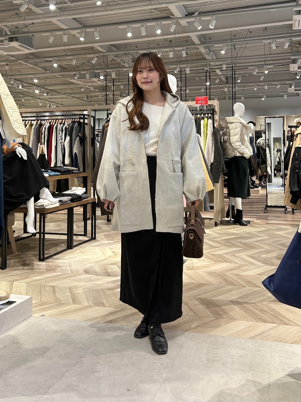 ホワイト系のニット/セーター、グレー系のスカート、ブラック系のブーツを着用したレディースの冬コーディネートの1枚目の写真