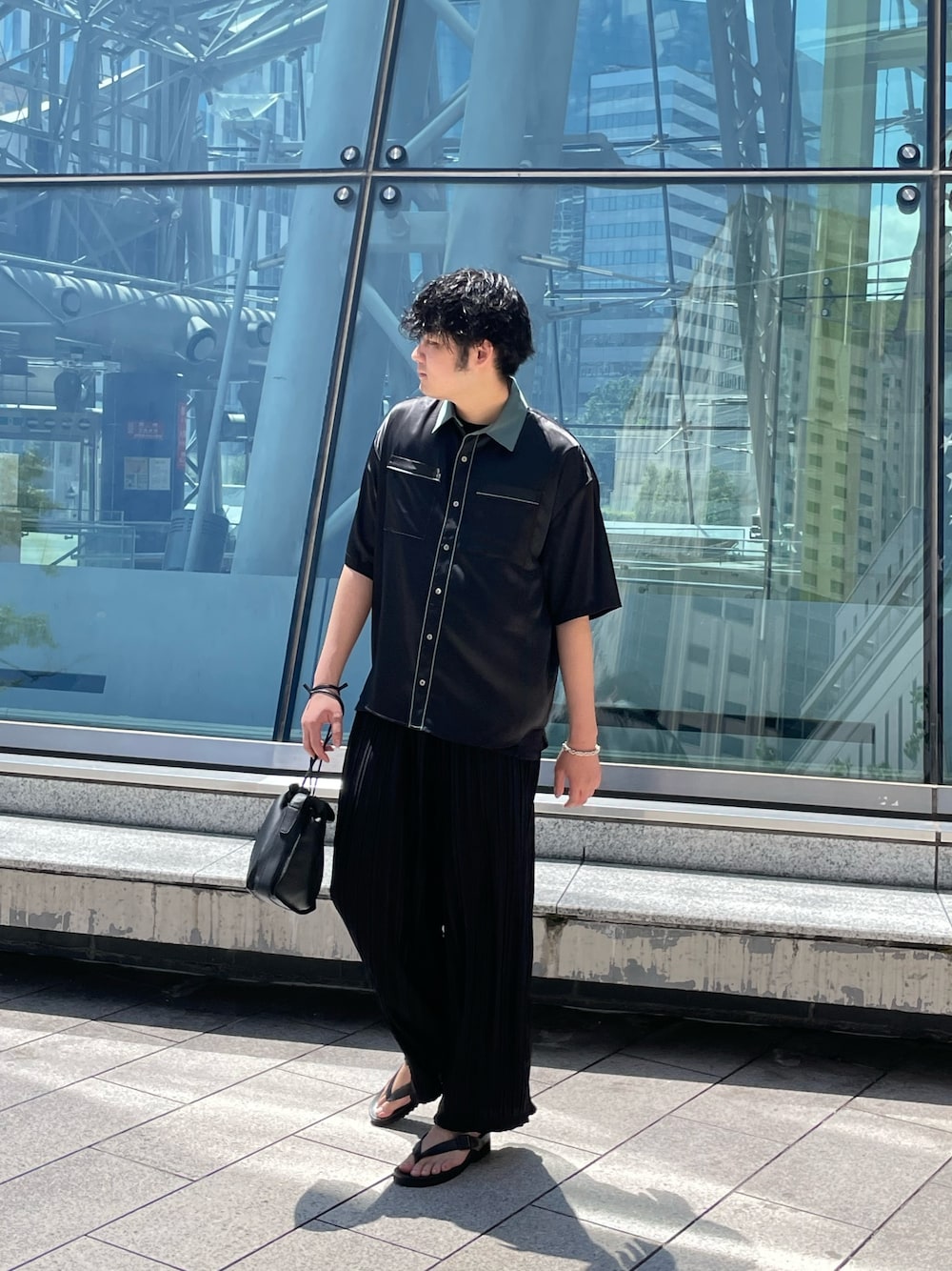 「オールブラック、クレリックシャツ、ショルダーバッグ、巾着バッグ、プリーツパンツ、ビーチサンダル、ビーサン、ワイドパンツ、ビッグシルエット、黒シャツ、半袖シャツ」｜「Lui'sの【Neucon / ニューコン】23SS クレリックパイピングシャツ（シャツ/ブラウス、ブラック系）」を使った、Shu ⠀Iizukaさん（メンズ・187cm）の夏コーディネートの1枚目の写真