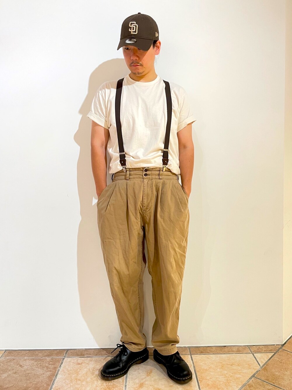 ベージュ系のTシャツ/カットソー、ベージュ系のチノパンツ、ブラック系のブーツを着用したメンズの夏コーディネートの1枚目の写真