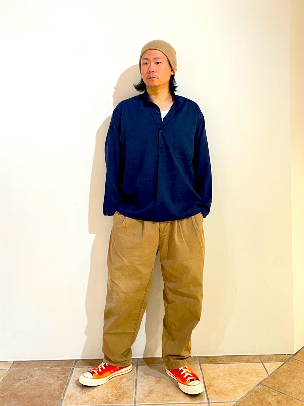 ブルー系のシャツ/ブラウス、ベージュ系のチノパンツ、オレンジ系のスニーカーを着用したメンズの秋コーディネートの1枚目の写真