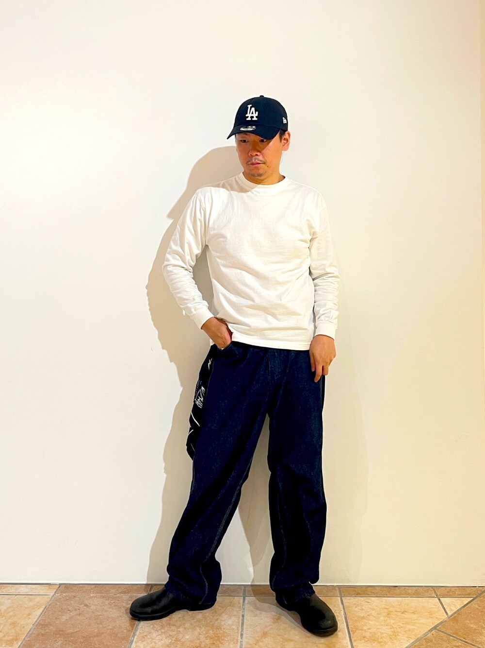 ホワイト系のTシャツ/カットソー、ブルー系のデニムパンツ、ブラック系のブーツを着用したメンズの秋コーディネートの1枚目の写真