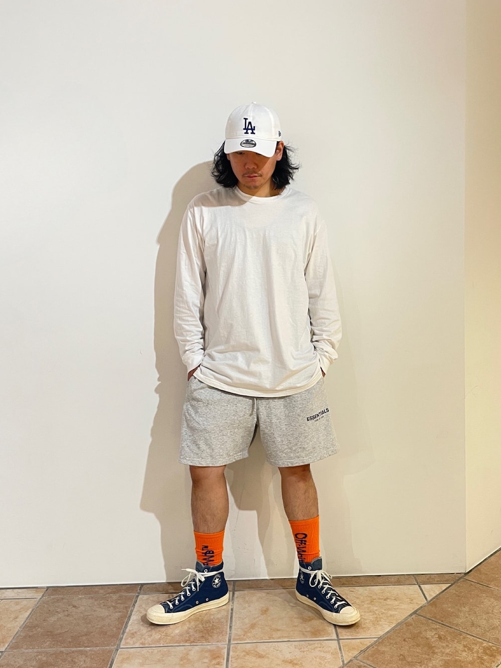 グレー系のスウェットパンツ、ブルー系のスニーカー、ホワイト系のキャップを着用したメンズの秋コーディネートの1枚目の写真