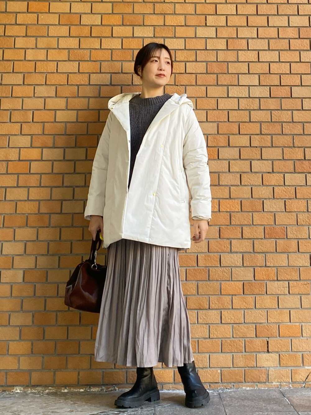 グレー系のニット/セーター、ホワイト系のダウンジャケット/コート、ベージュ系のスカートを着用したレディースの冬コーディネートの1枚目の写真