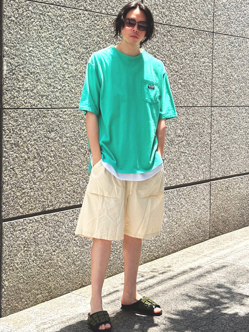 グリーン系のTシャツ/カットソー、ベージュ系のその他パンツ、ブラック系のサンダルを着用したメンズの夏コーディネートの1枚目の写真