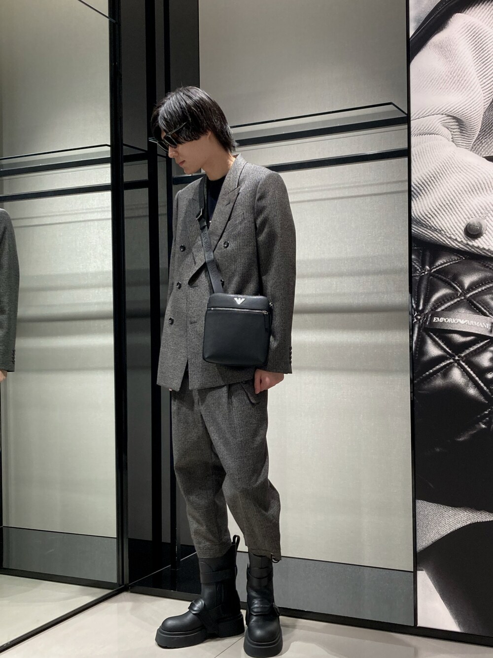 グレー系のテーラードジャケット、ブルー系のTシャツ/カットソー、ブラック系のショルダーバッグを着用したメンズの秋コーディネートの1枚目の写真