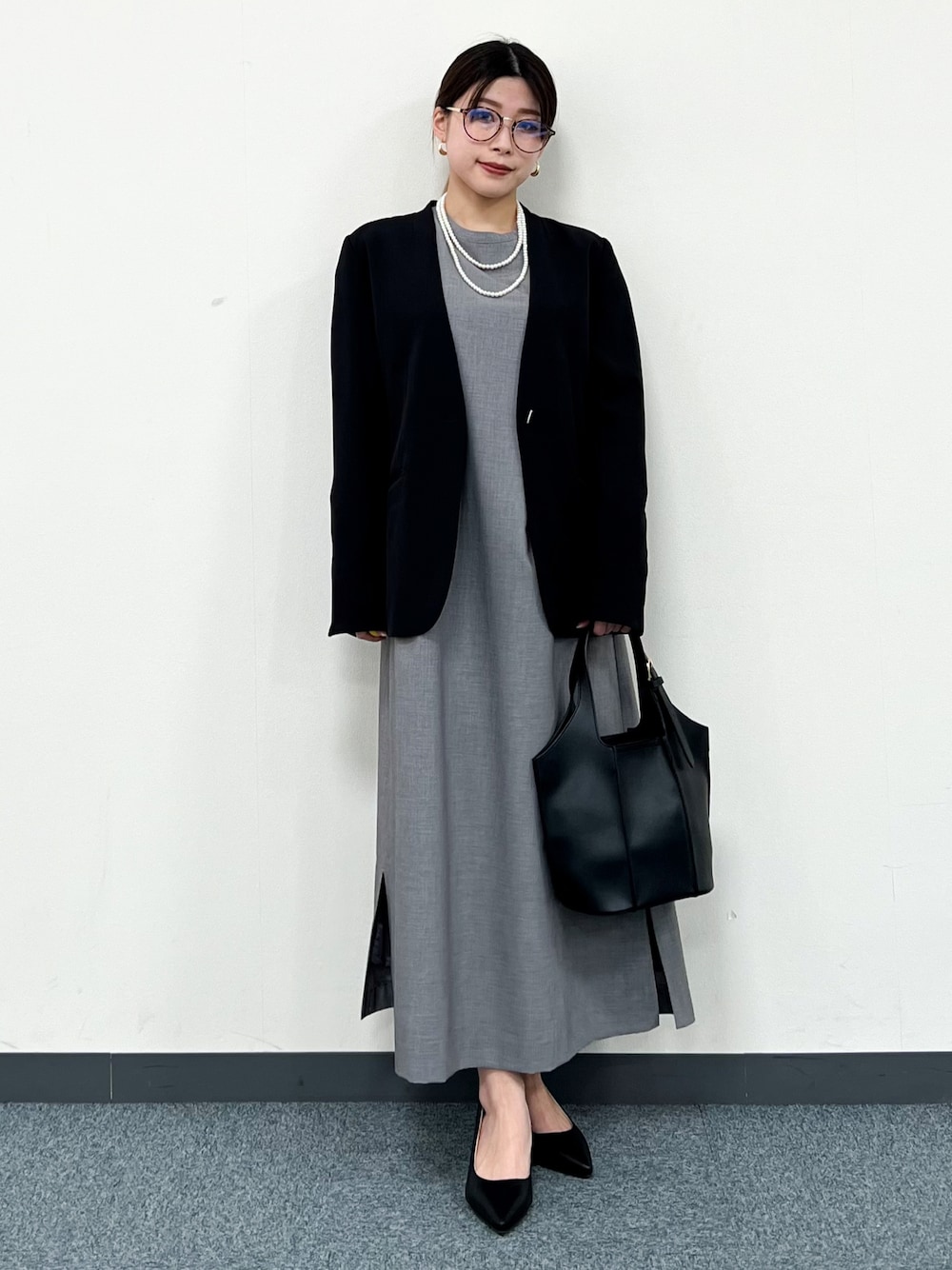 ブラック系のノーカラージャケット、グレー系のワンピース、ブラック系のトートバッグを着用したレディースの冬コーディネートの1枚目の写真