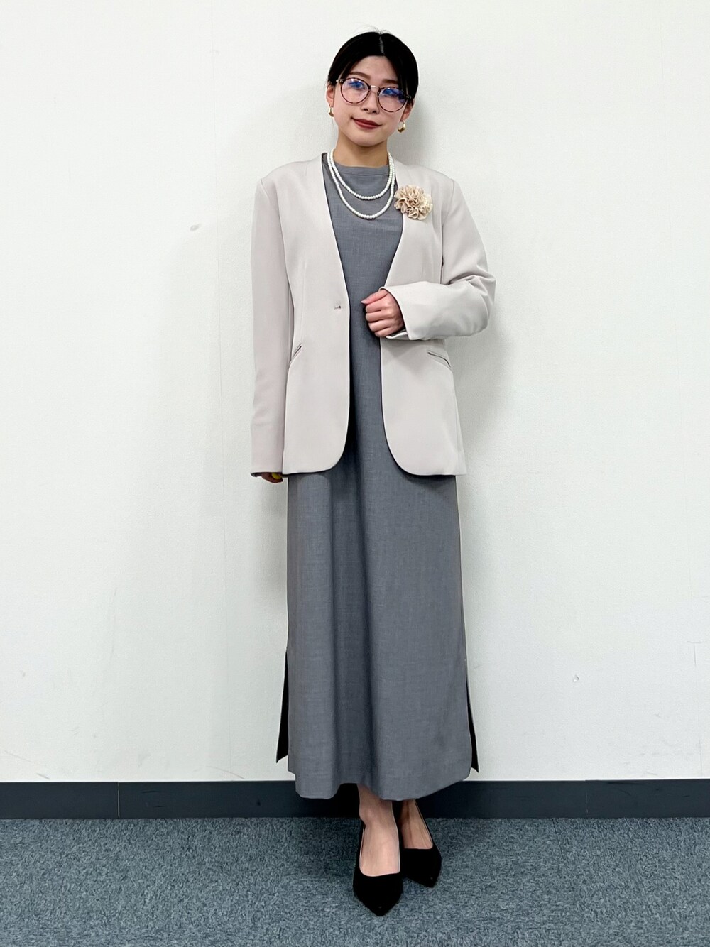 グレー系のノーカラージャケット、グレー系のワンピース、ブラック系のパンプスを着用したレディースの冬コーディネートの1枚目の写真