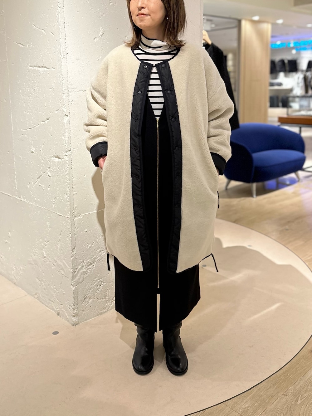 ホワイト系のダウンジャケット/コート、ブラック系のワンピース、ホワイト系のニット/セーターを着用したレディースの秋コーディネートの1枚目の写真