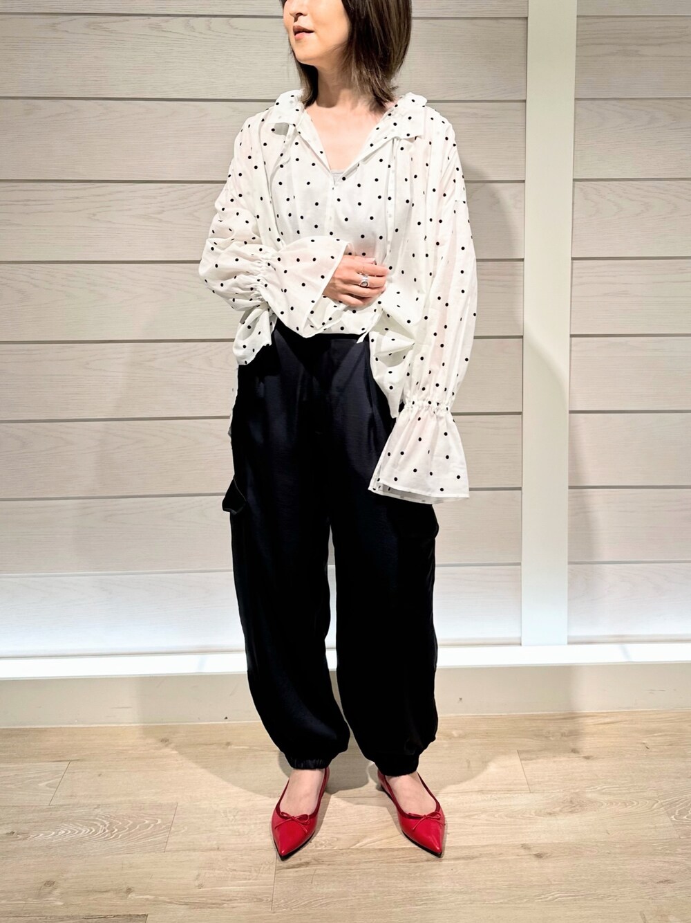 レッド系のパンプス、ホワイト系のシャツ/ブラウス、ブルー系のカーゴパンツを着用したレディースの秋コーディネートの1枚目の写真