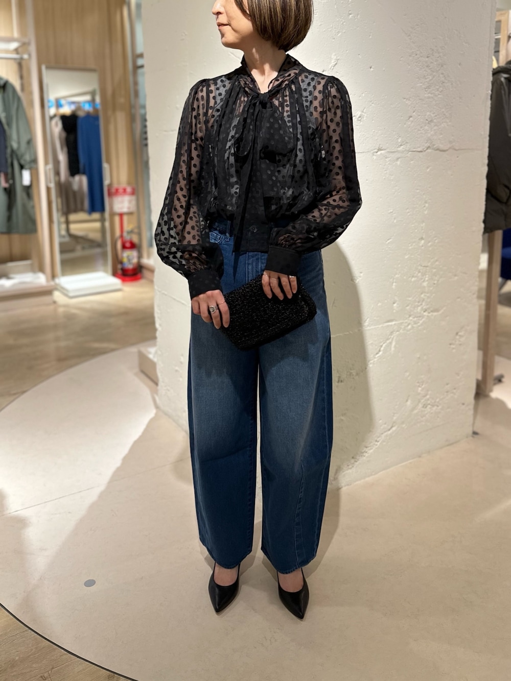 ブラック系のシャツ/ブラウス、ブラック系のパンプス、ブルー系のデニムパンツを着用したレディースの冬コーディネートの1枚目の写真