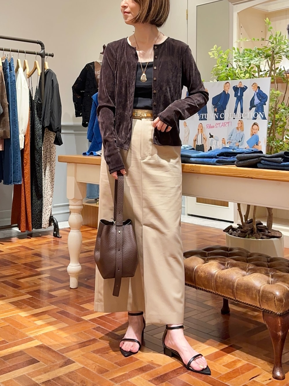 ベージュ系のスカート、ブラウン系のショルダーバッグ、ブラウン系のカーディガン/ボレロを着用したレディースの秋コーディネートの1枚目の写真