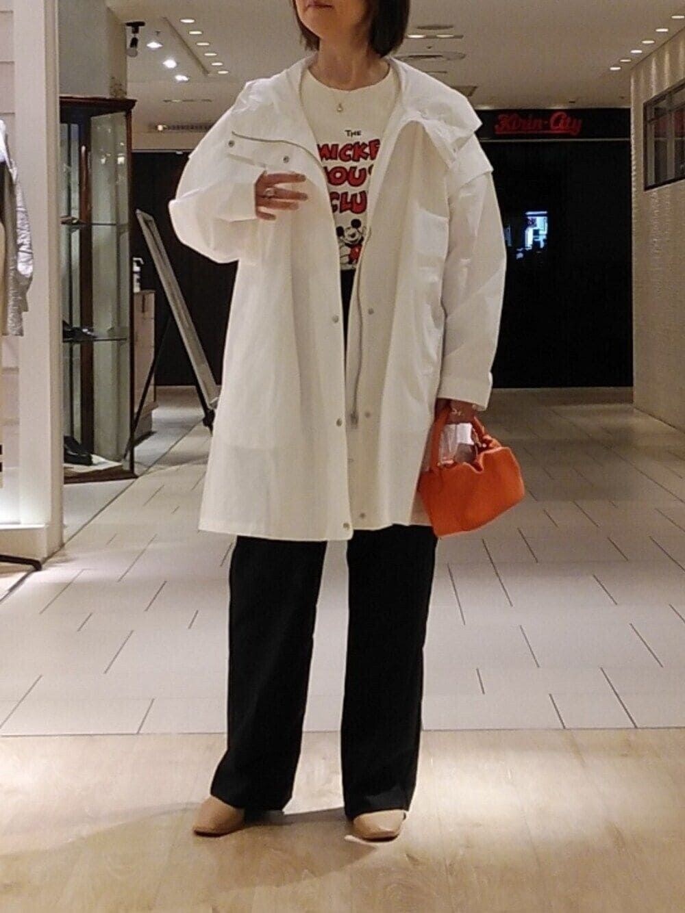 ホワイト系のブルゾン、ブラック系のスラックス、オレンジ系のトートバッグを着用したレディースの春コーディネートの1枚目の写真