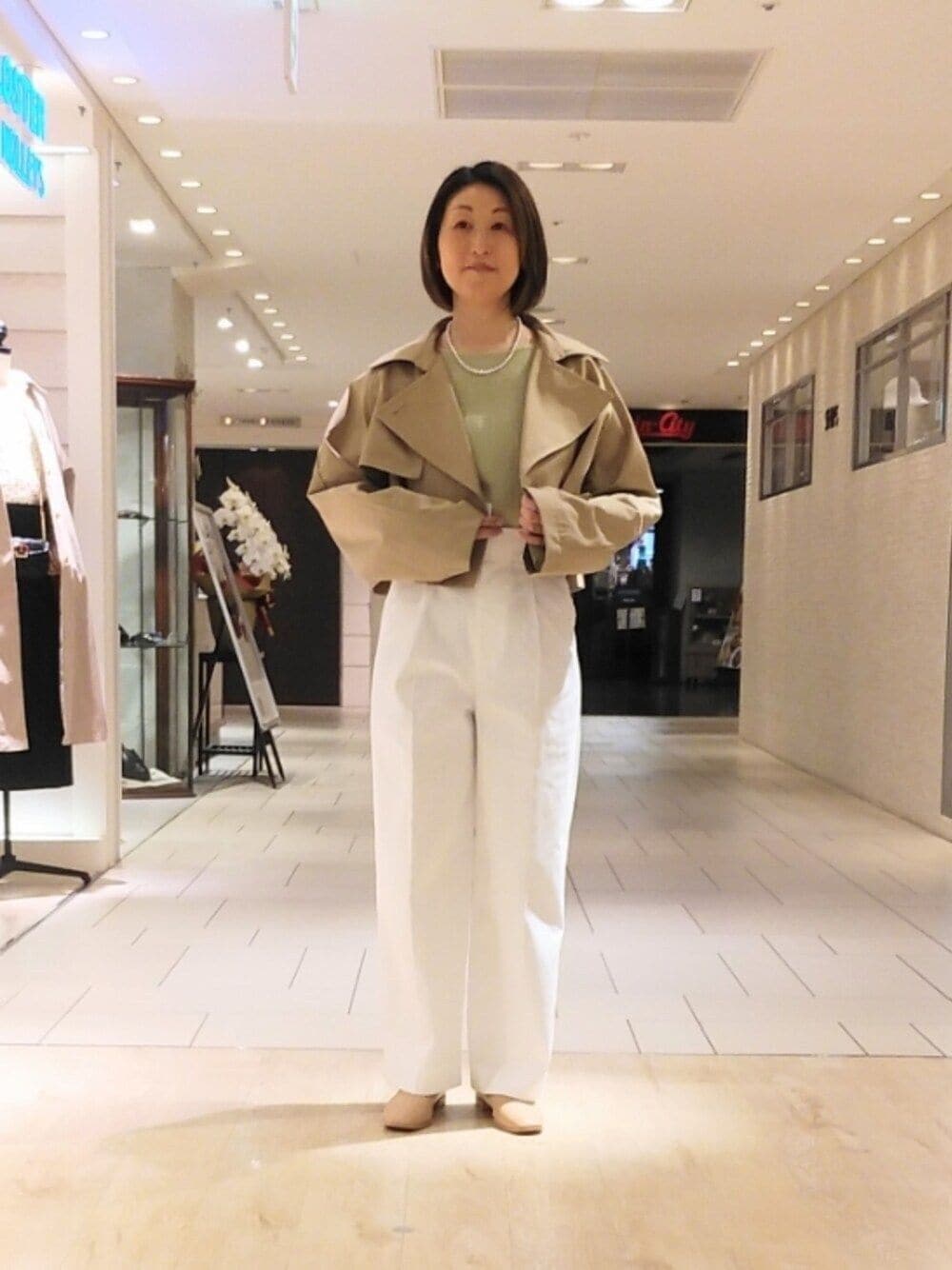 ベージュ系のトレンチコート、グリーン系のシャツ/ブラウス、ホワイト系のその他パンツを着用したレディースの春コーディネートの1枚目の写真