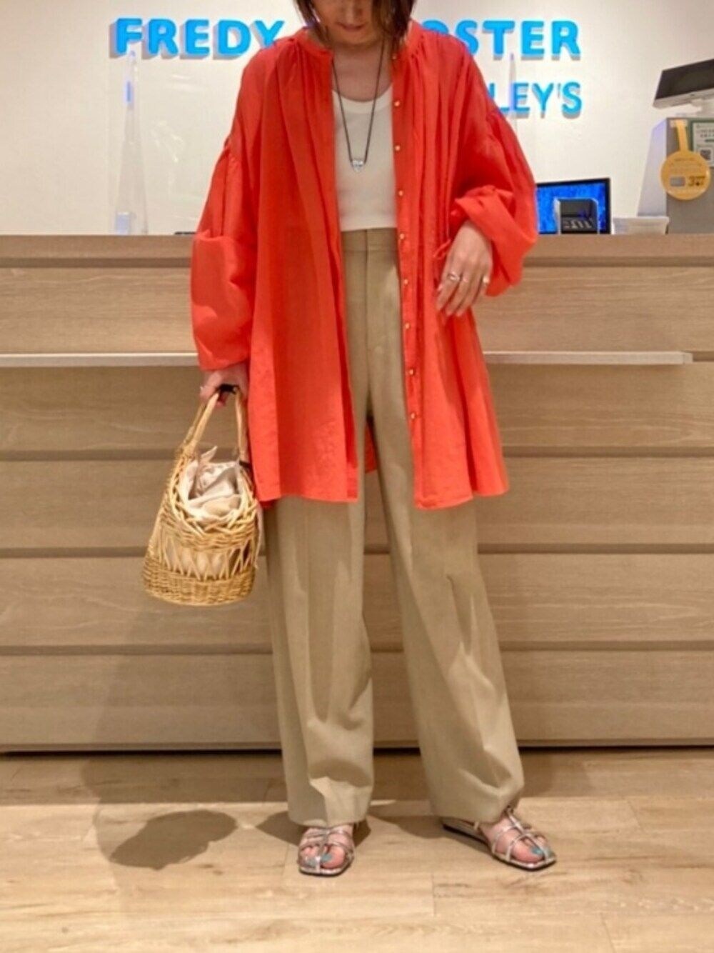 レッド系のシャツ/ブラウス、ベージュ系のその他パンツ、ベージュ系のかごバッグを着用したレディースの春コーディネートの1枚目の写真