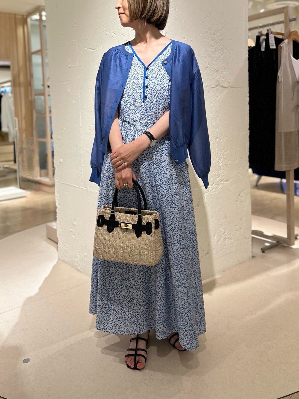 ブラック系のかごバッグ、ブルー系のカーディガン/ボレロ、ブルー系のワンピースを着用したレディースの夏コーディネートの1枚目の写真