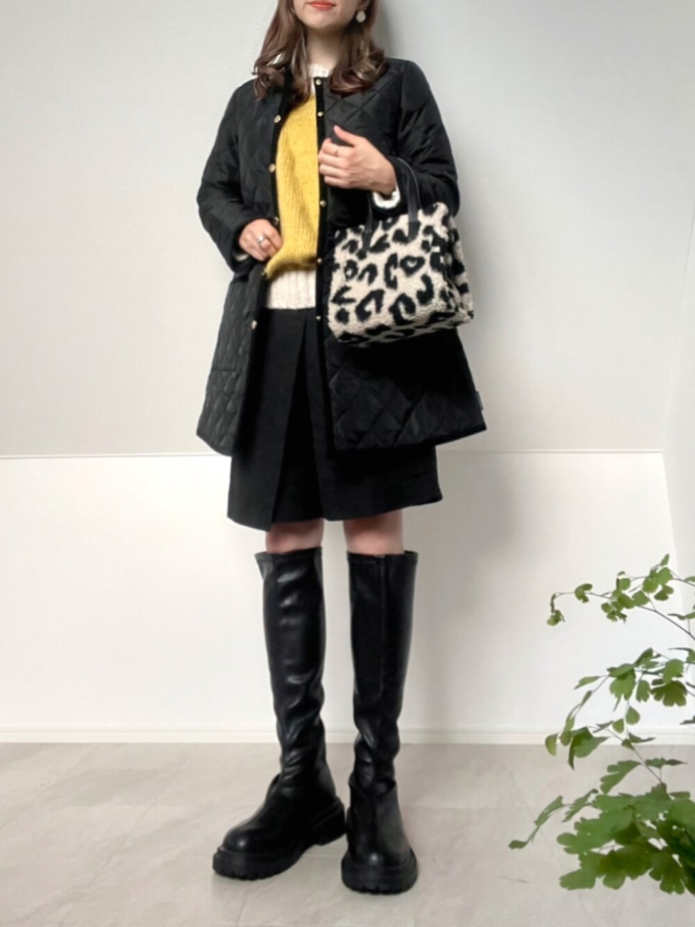 ブラック系のその他アウター、イエロー系のニット/セーター、ブラック系のブーツを着用したレディースの秋コーディネートの1枚目の写真