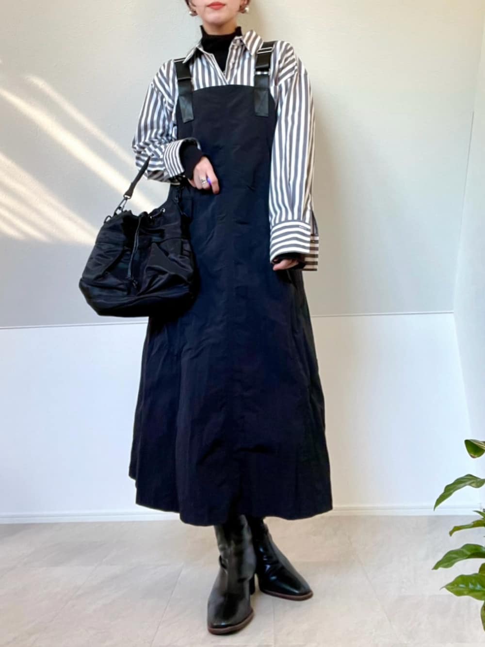 ブラック系のメッセンジャーバッグ、ブラック系のジャンパースカート、ブラック系のシャツ/ブラウスを着用したレディースの冬コーディネートの1枚目の写真