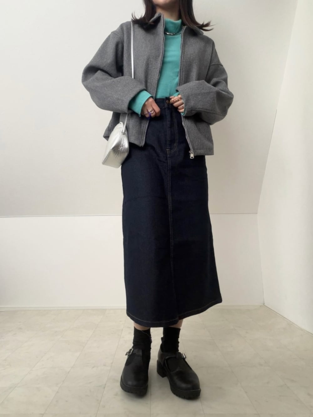 ブルー系のデニムスカート、シルバー系のショルダーバッグ、グレー系のジャケット/アウターを着用したレディースの冬コーディネートの1枚目の写真
