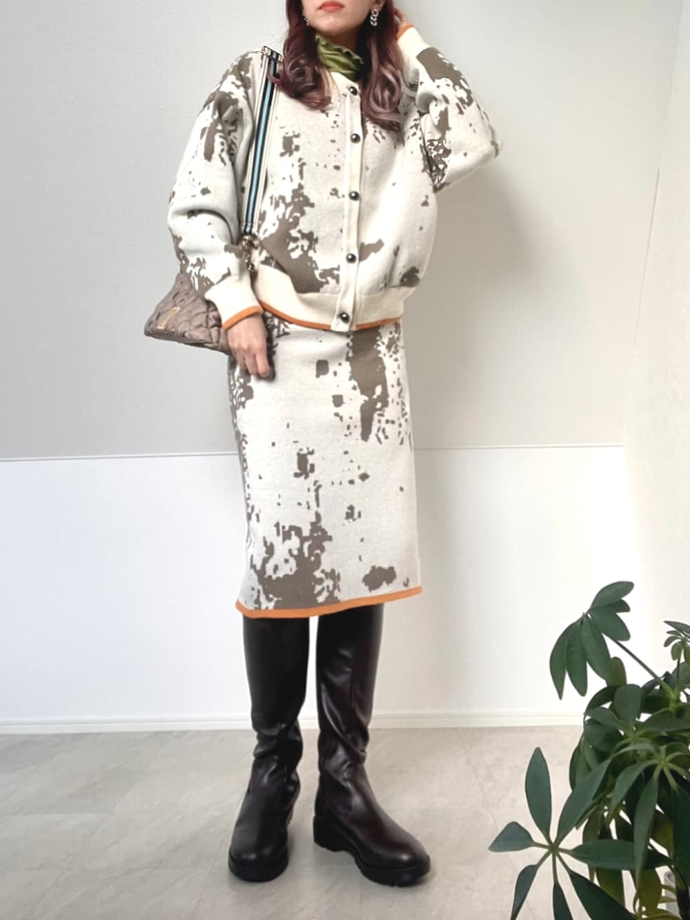 ホワイト系のカーディガン/ボレロ、ホワイト系のスカート、ブラウン系のブーツを着用したレディースの冬コーディネートの1枚目の写真