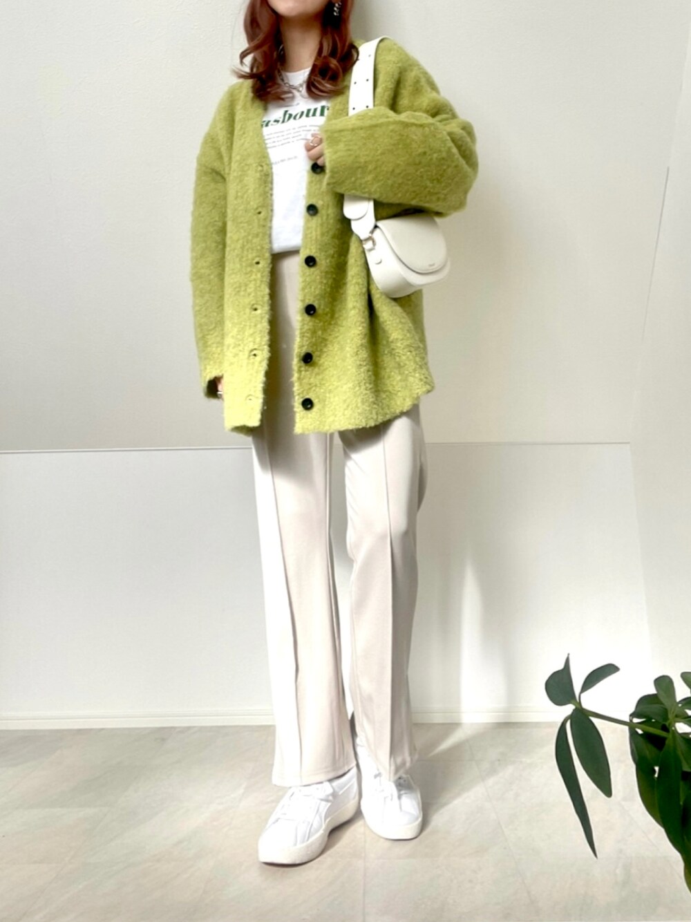 グリーン系のカーディガン/ボレロ、ホワイト系のTシャツ/カットソー、ホワイト系のショルダーバッグを着用したレディースの冬コーディネートの1枚目の写真