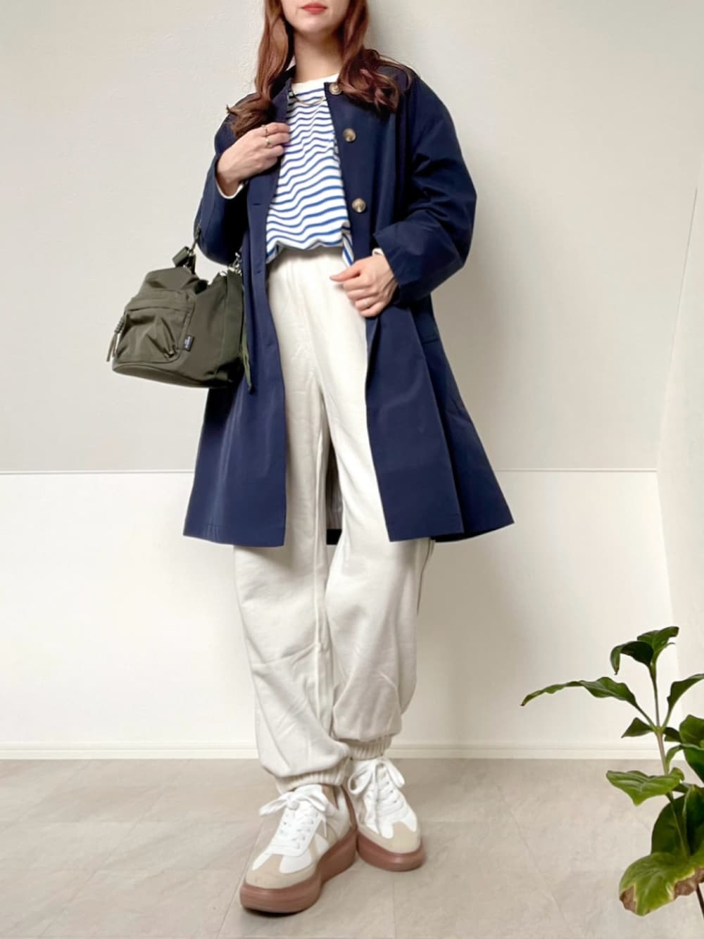 ブルー系のステンカラーコート、グリーン系のショルダーバッグ、ブルー系のTシャツ/カットソーを着用したレディースの春コーディネートの1枚目の写真